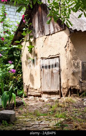 Alte cob Ziege Haus mit Holztür in einem grünen Garten. Traditionelle alte Dorf Architektur. Kaniv Bezirk, Region Cherkasy, Ukraine Stockfoto