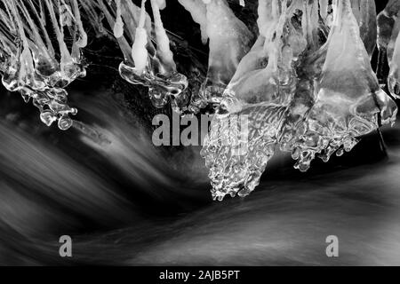 Schnell fließenden Bach mit überhängenden Eiszapfen im Winter Stockfoto