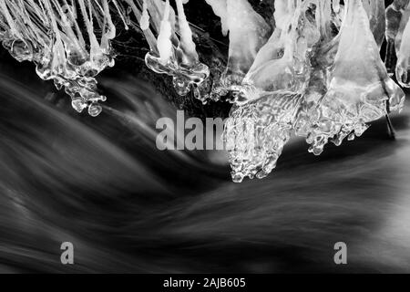 Schnell fließenden Bach mit überhängenden Eiszapfen im Winter Stockfoto