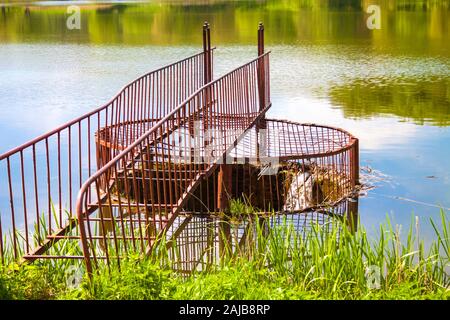 Hochwasserentlastung mit Metall Geländer auf den Wald See. Holosiivskyi Nationalpark in Kiew, Ukraine Stockfoto