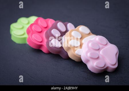 Cute farbige paw Form Seife auf dunklen dunklen Hintergrund Stockfoto