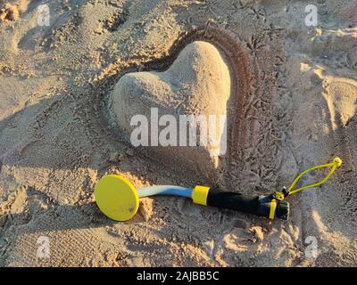 Das Foto von einem Unterwasser Metalldetektor und einem Sand Herz am Strand. Schatz suchen und touristische Abenteuer Hintergrund. Stockfoto