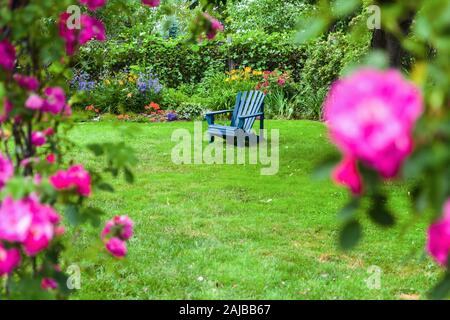 Ein rasen Stuhl auf dem Rasen in einem Rosengarten. Stockfoto