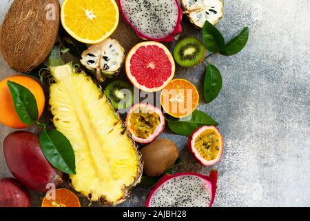 Exotische Asien Obst Hintergrund. Sortierte reif saftig tropischer Sommer Obst der Saison auf einem grauen Stein. Ansicht von oben flach Hintergrund. Stockfoto