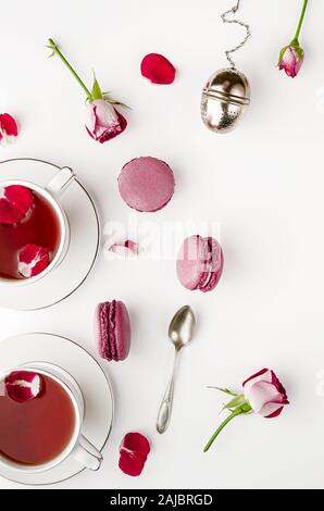 Frühstück Tee am weißen Tisch mit Rosen und Makronen für Zwei. Vallentines Tag und Romantik Konzept. Flach, von oben nach unten Stockfoto