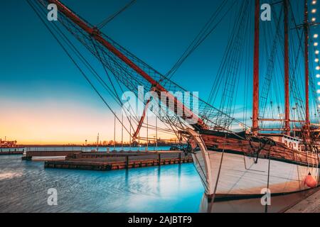 Helsinki, Finnland. Alte hölzerne Segelboot Schiff Schoner ist City Pier, Steg vertäut. Beleuchtung am Abend oder in der Nacht die Beleuchtung. Stockfoto