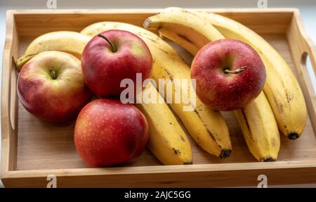 Eine hölzerne Obstteller mit reife Bananen und Äpfel. Stockfoto