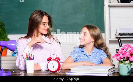 Hausaufgaben mit Mama. Kleine Mädchen und Frau sitzen am Schreibtisch. Schule Bildung. Gemeinsam studieren. Hilfe bei den Hausaufgaben. Hausaufgaben Projekt. Schwester helfen beim Lernen. Lehrer Art Dame mit Pupille. Stockfoto