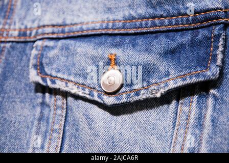 Nahaufnahme der Brusttasche der Jeansjacke mit Klappe und Knopf aus Metall Stockfoto