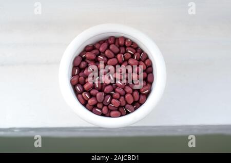 Ungekocht Adzuki Bohnen, auch azuki oder aduki Beans in einer weißen Schüssel genannt. Diese Hülsenfrüchte sind gesunde vegane oder vegetarische Gerichte. Stockfoto