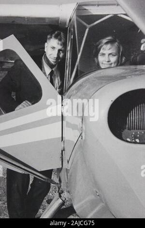 Feine Schwarzweißfotografie der 1960er Jahre eines sehr glücklichen Paares, das in ihrem Flugzeug sitzt und den Lebensstil der Düseneinstellung ansetzt Stockfoto