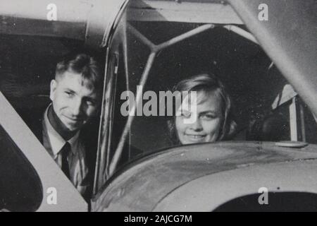 Feine Schwarzweißfotografie der 1960er Jahre eines sehr glücklichen Paares, das in ihrem Flugzeug sitzt und den Lebensstil der Düseneinstellung ansetzt Stockfoto