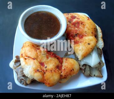 Heiße französische dip Sandwich mit geschmolzenem Mozzarella Käse auf ein frisches Brot mit faccocia Sonne serviert getrockneten Tomaten und eine Tasse au Jus Stockfoto