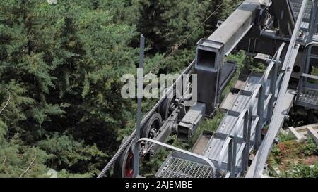 Mechanismus drehende Räder dreht sich bewegenden Seilbahn über dem dichten, grünen Wald und muslimischen Friedhof Ansicht schließen Stockfoto