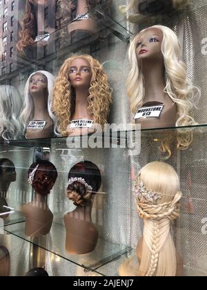 Eine Vielzahl von Perücken sind auf Mannequins in einem Schaufenster. Stockfoto