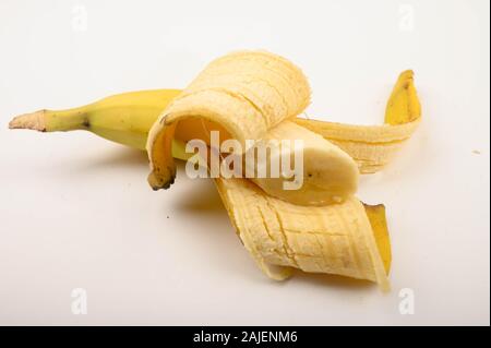 Eine halbe reife, gelbe teilweise geschälte Banane auf einem weißen Hintergrund. Nahaufnahme Stockfoto