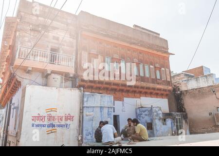 Jodhpur, Indien - 07 März 2017: Blaue Wände der Stadt und der Mann sitzt im Schatten. Stockfoto