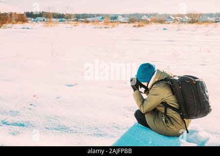 Junge Frau touristische Lady Foto Fotos von verschneite Landschaft im sonnigen Wintertag. Aktiver Lebensstil mit Rucksack und Kamera. Stockfoto