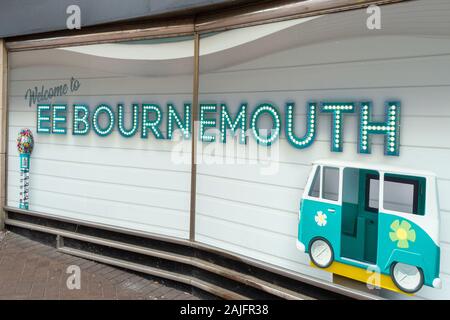 Schaufensterausstellung im EE-Geschäft in Bournemouth, Großbritannien. Beleuchtetes „Welcome to EE BOURNEMOUTH“-Schild in blauen Lichtern mit türkisfarbener Retro-Grafik für Wohnmobile Stockfoto