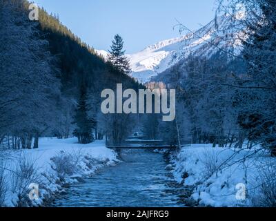 Eine Misty Mountain Stream fließt durch eine verschneite Landschaft. Die Bäume und Felsen sind mit Schnee bedeckt ein perfekter Winter ruhige Szene zu erstellen. Stockfoto