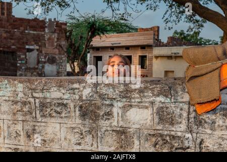 Jodhpur, Indien - 08.März 2017: fröhliches Mädchen wacht über Zaun. Stockfoto