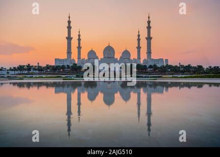 Abu Dhabi, VAE, Vereinigte Arabische Emirate: Abu Dhabi, Sheikh Zayed Moschee (auch bekannt als Grand Mosque) in der Dämmerung, der Reflexion im Wasser, bei Sonnenuntergang Stockfoto