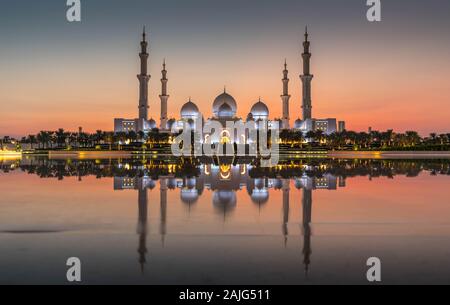 Abu Dhabi, VAE, Vereinigte Arabische Emirate: Abu Dhabi, Sheikh Zayed Moschee (auch bekannt als Grand Mosque) in der Dämmerung, der Reflexion im Wasser, bei Sonnenuntergang Stockfoto