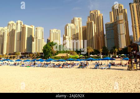 Dubai / VAE - 7. November 2019: JBR. Wunderschöne Aussicht auf die Wolkenkratzer der Jumeirah Beach Residence. Stadtstrand im Nahen Osten. Blaue Sonnenliegen. Stockfoto