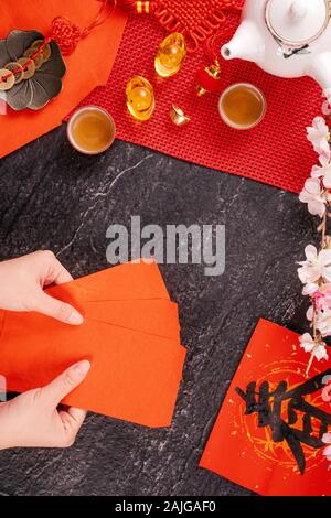 Design Konzept der Chinesischen Mondkalender Januar Neujahr - Woman Holding, die roten Briefumschläge (ang Pow, Hong Bao) für Glück, Geld, Ansicht von oben, flach, overhe Stockfoto