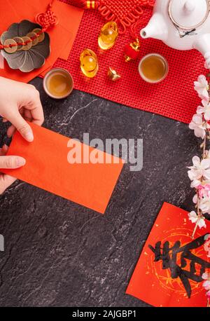 Design Konzept der Chinesischen Mondkalender Januar Neujahr - Woman Holding, die roten Briefumschläge (ang Pow, Hong Bao) für Glück, Geld, Ansicht von oben, flach, overhe Stockfoto