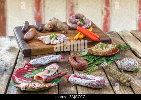 Auswahl an französischen raw Charcuterie Bord, mit Rucola Blätter und trockene Wurst über alten roten Fachwerkhaus Wand Hintergrund. Stockfoto