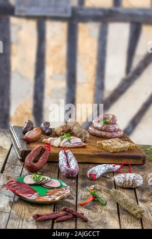 Auswahl an französischen raw Charcuterie Bord, mit Rucola Blätter und trockene Wurst über alte braune gezimmerten Wand Hintergrund. Stockfoto