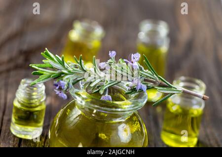 Rosmarin in Blume auf einer Aromatherapie Ätherische Öl blaues Glas Flasche, auf weißem Hintergrund Stockfoto