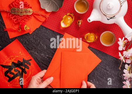 Design Konzept der Chinesischen Mondkalender Januar Neujahr - Woman Holding, die roten Briefumschläge (ang Pow, Hong Bao) für Glück, Geld, Ansicht von oben, flach, overhe Stockfoto