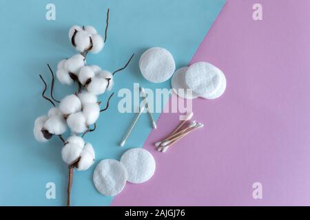 Wattestäbchen und Polster mit flauschige Baumwolle Blumen auf rosa Hintergrund der Ansicht von oben. Flach. Kopieren Sie Platz für Ihren Text. Stockfoto