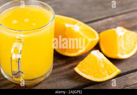 Glas frisch gepresster Orangensaft mit frischen Früchten auf hölzernen Tisch Stockfoto