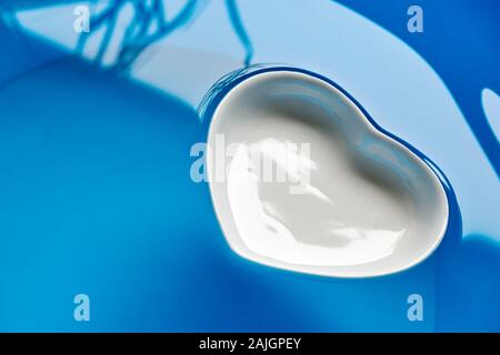 Porzellan weiß Herz floating auf sauberen blauen Wasser für die Verwendung als valentine Hintergrund oder ein Konzept von einem sauberen Meer Stockfoto