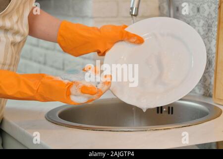 Nahaufnahme von Frau Hände in Handschuhen Geschirr in der Küche Stockfoto
