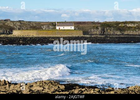 Blick über die Bucht zu 12. Jahrhundert St Cwyfan's oder Llangwyfan Insel Kirche in das Meer bei Ebbe. Porth Cwyfan, Aberffraw, Isle of Anglesey, Wales, Großbritannien Stockfoto