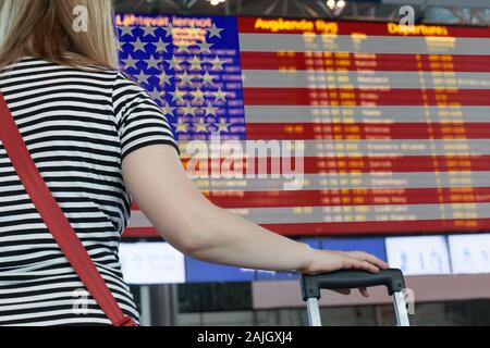 Frau sieht die Anzeigetafel am Flughafen. Wählen Sie ein Land aus USA für Reisen oder Migration. Stockfoto