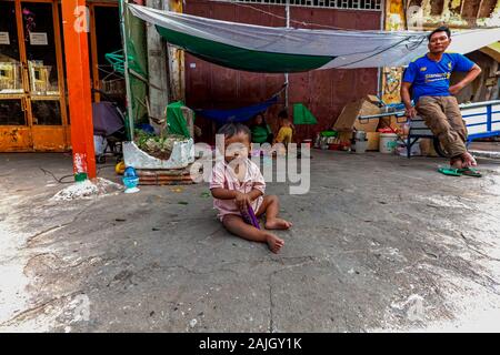 Einen armen jungen asiatischen Jungen Kleinkind sitzt auf einem Bürgersteig vor Tierheim ist seine heimatlosen Familie in Kampong Cham, Kambodscha. Stockfoto