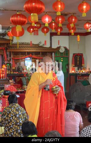 Ein buddhistischer Priester segnet einige Menschen in einem Tempel vor der chinesischen Neujahrsfeier. Stockfoto