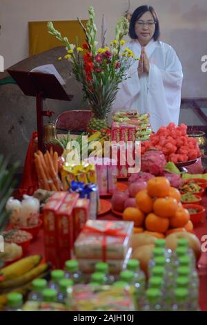 Eine Mönchin betet vor einem Altar mit Opfergaben. Stockfoto