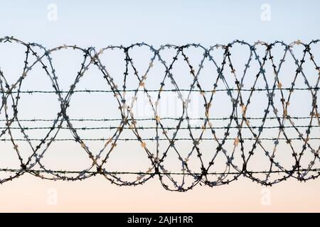 W gerappten Stacheldrahtzaun mit Spikes und Himmel im Hintergrund. Verrosteter Maschendrahtzaun guarding hohe Sicherheit Einrichtung wie Flughafen, Gefängnis Stockfoto