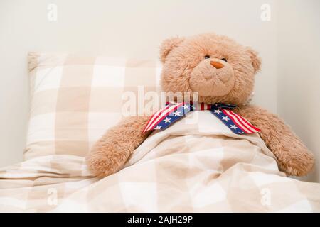 Teddybär schlafen in einem Bett mit amerikanischen Simpsons. Plüsch Spielzeug in Decken auf der Tag der Unabhängigkeit Stockfoto
