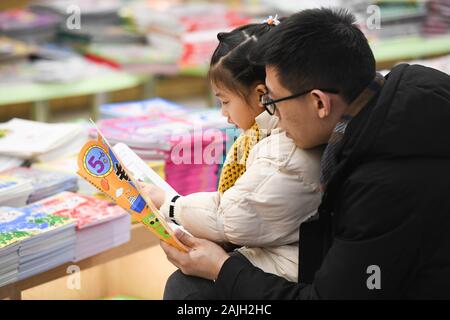 Hefei, Anhui Provinz Chinas. Am 4. Januar, 2020. Ein Mann und ein Mädchen mit einem Buch in einer Buchhandlung in Hefei, Osten Chinas Provinz Anhui, Jan. 4, 2020. Credit: Zhang Duan/Xinhua/Alamy leben Nachrichten Stockfoto