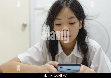 Junge Schulmädchen zu Handy Spiele süchtig. Macht ihn nicht in der Hausarbeit zu interessieren. Stockfoto