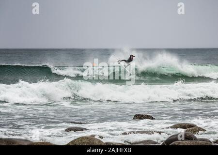 Arktis Surfer Surfen in der Norwegischen See. Unstad, Norwegischen Dorf auf der Lofoten. Norwegische Küste. Winter Wasser Sport. Uttakle Stockfoto