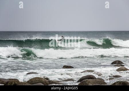 Arktis Surfer Surfen in der Norwegischen See. Unstad, Norwegischen Dorf auf der Lofoten. Norwegische Küste. Winter Wasser Sport. Uttakle Stockfoto