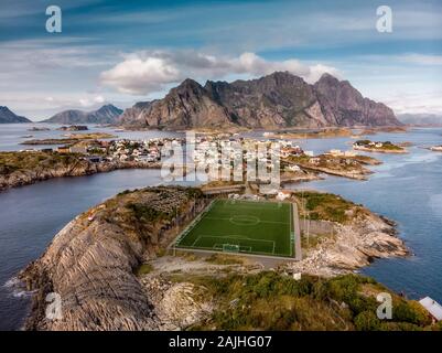 Unglaubliche Luftaufnahme von henningsvær, seine malerische Fußballplatz und die Berge im Hintergrund. Ein kleines Fischerdorf auf mehrere kleine ist Stockfoto